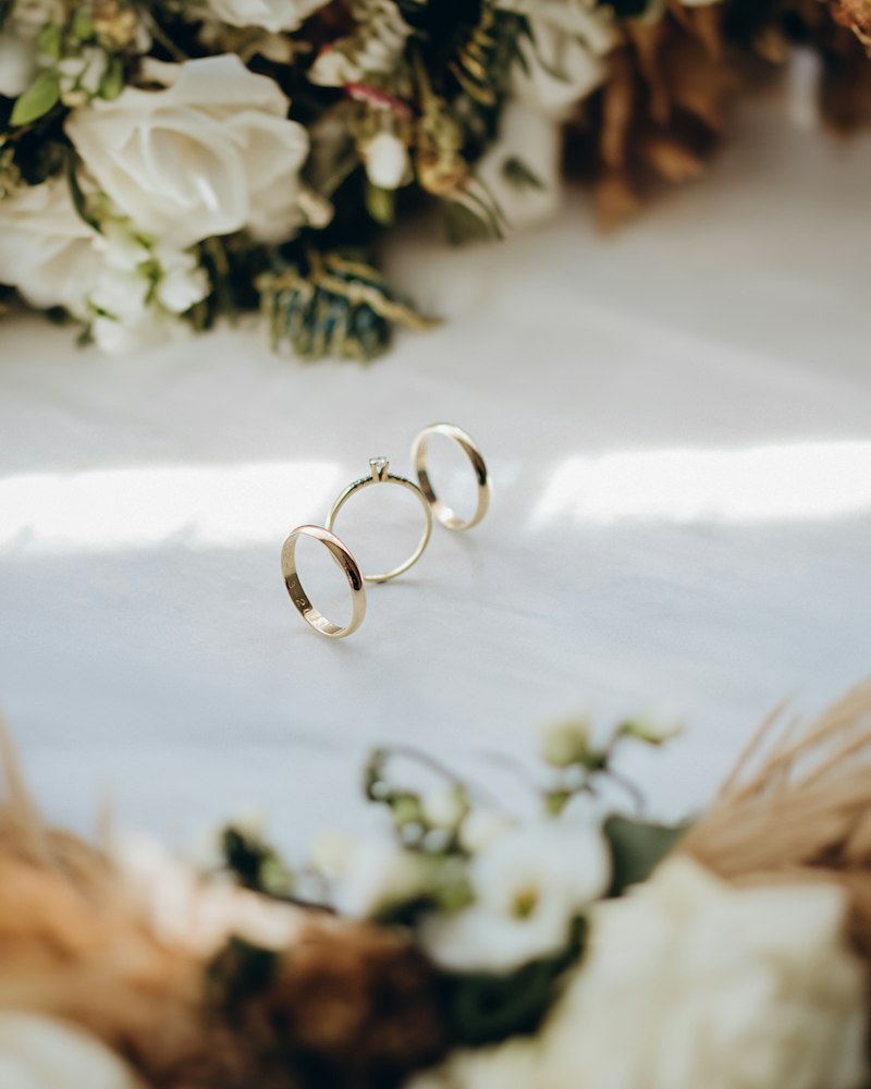 Two wedding rings sitting on top of a bouquet of flowers