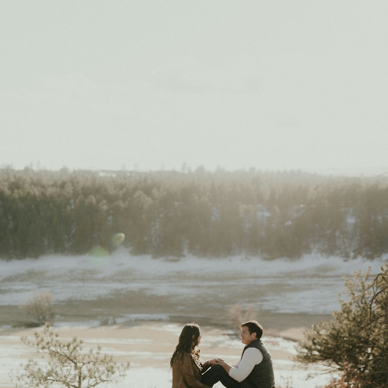 A couple sitting together on a rock in the mountains