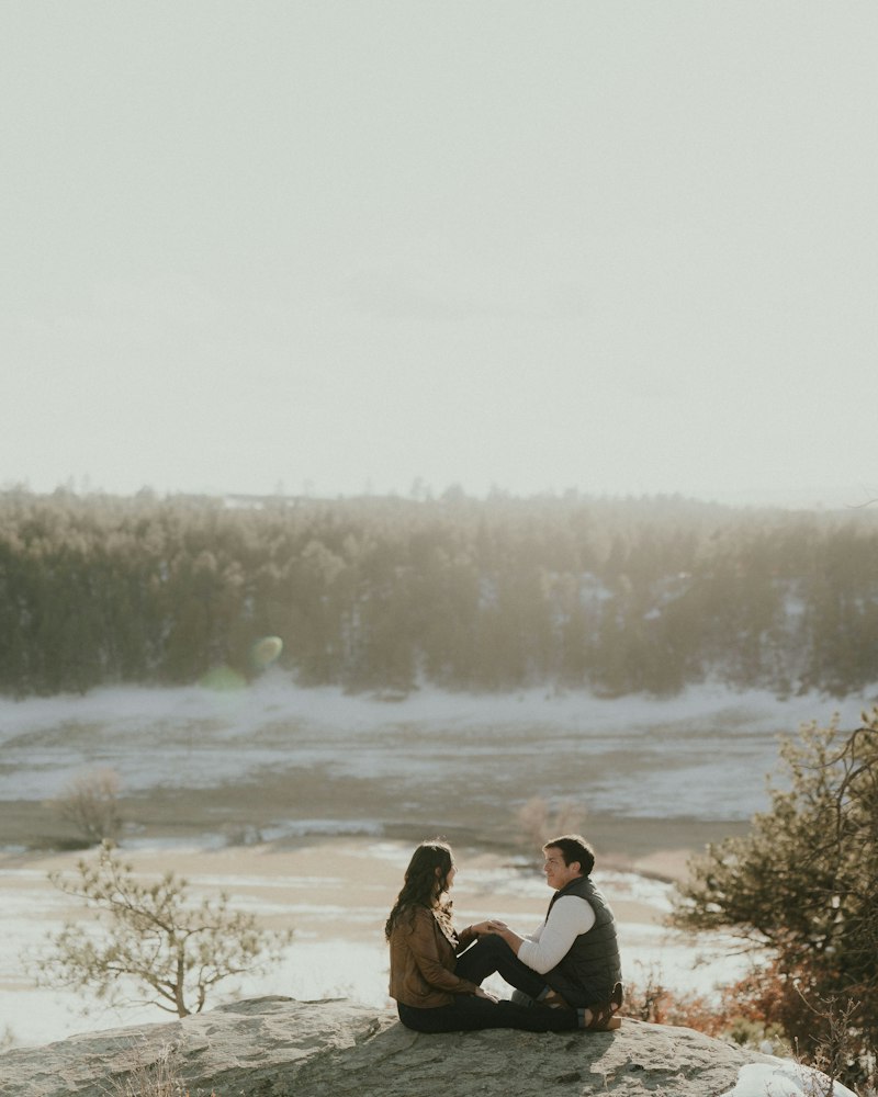 A couple sitting together on a rock in the mountains