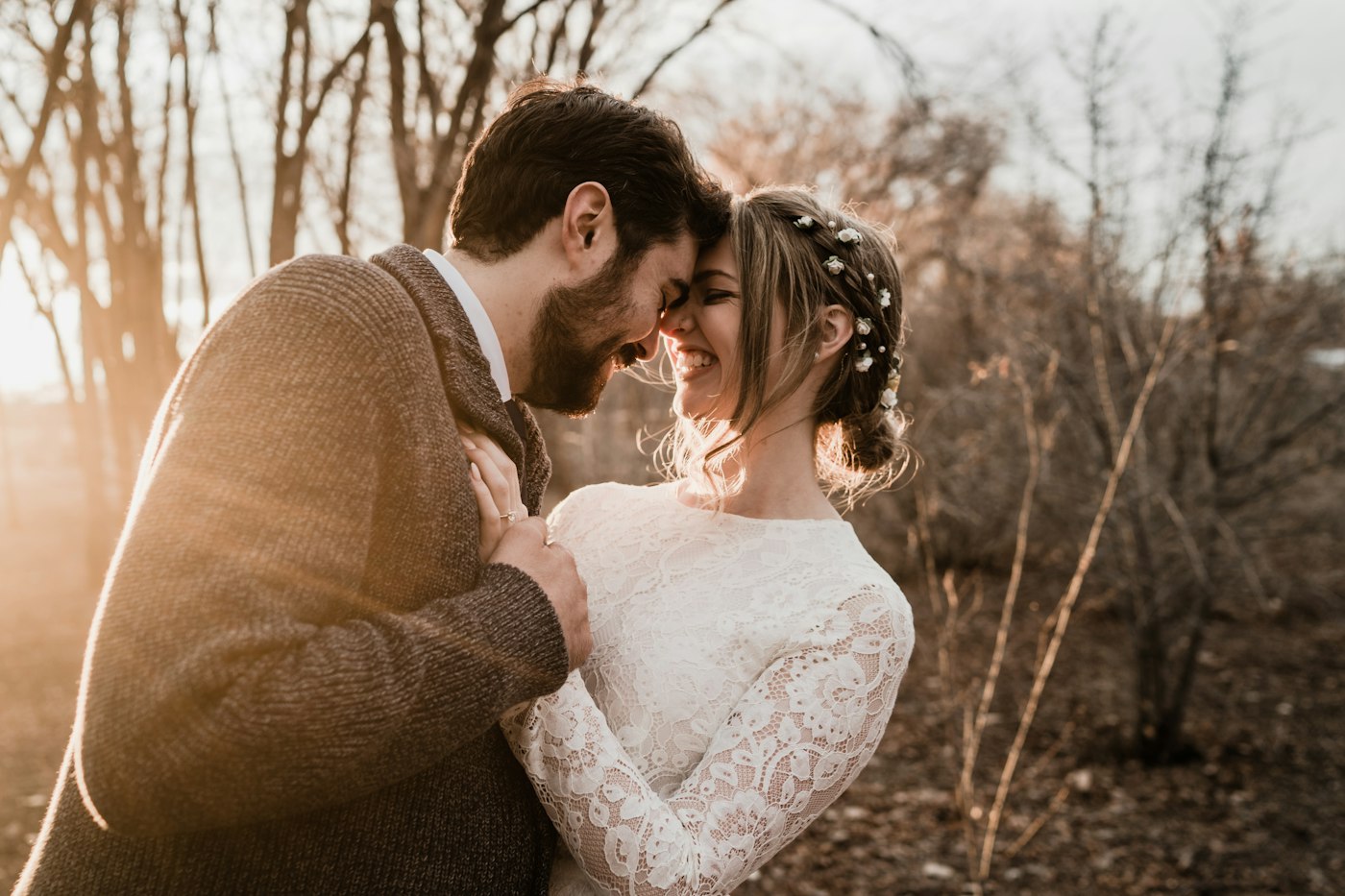 A bride and groom standing close together among trees
